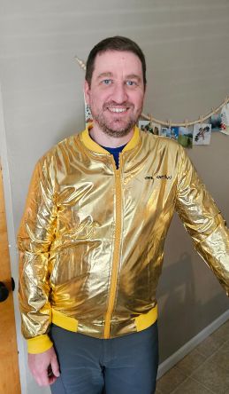 Jeff Zemerick wearing the AWS gold jacket, a metallic gold bomber jacket with yellow ribbed cuffs and collar and an AWS Certified logo embroidered on the chest.